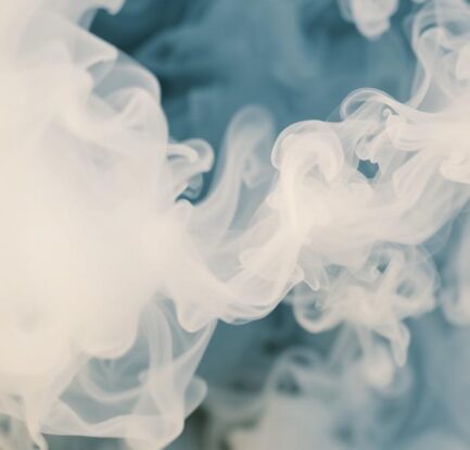 Swirling white smoke clouds against a soft blue background, creating elegant, flowing abstract patterns.